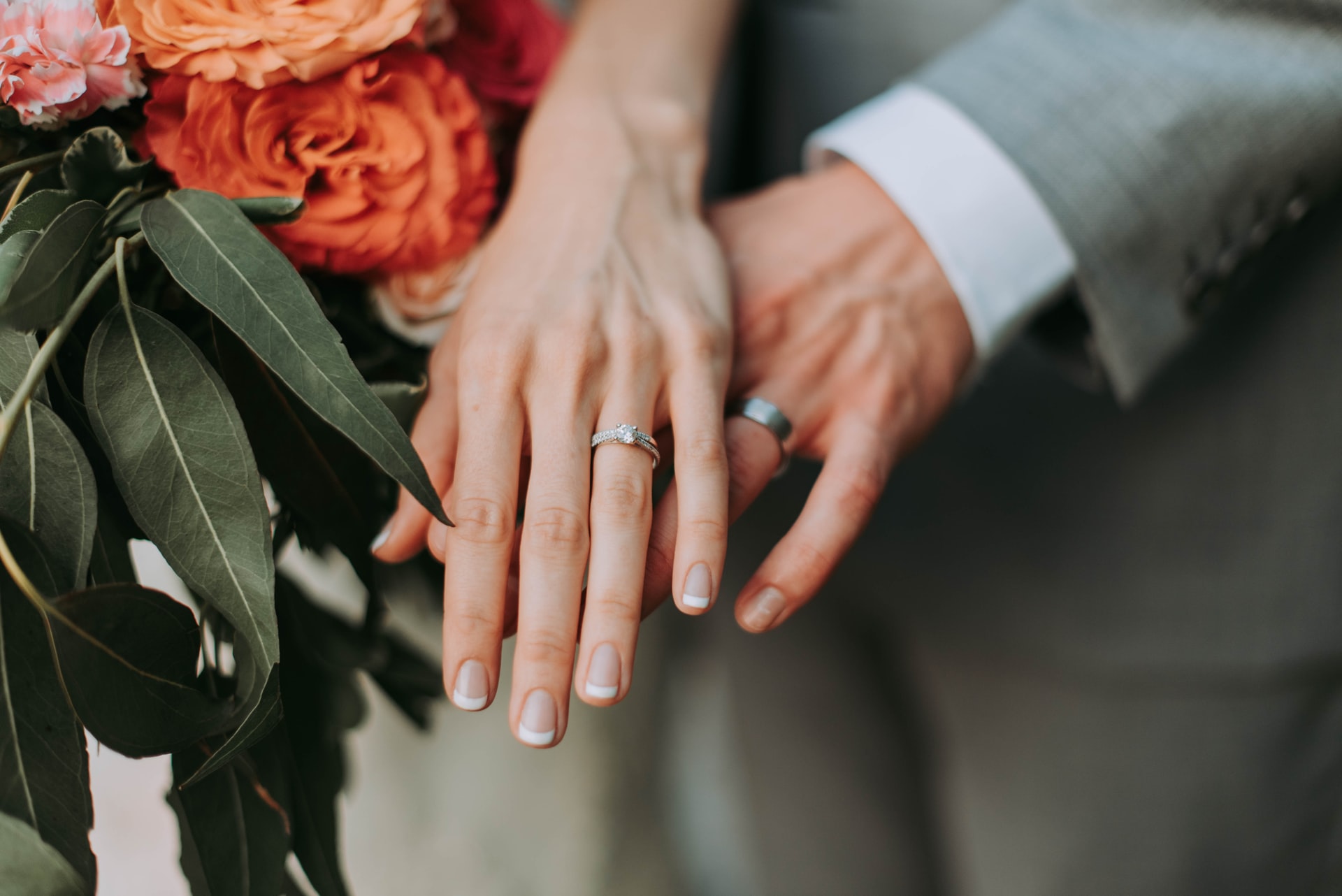 Closeup photo of wedding rings on hands of a couple